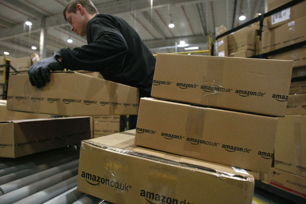 A worker carries packages for shipment at the Amazon warehouse in Leipzig